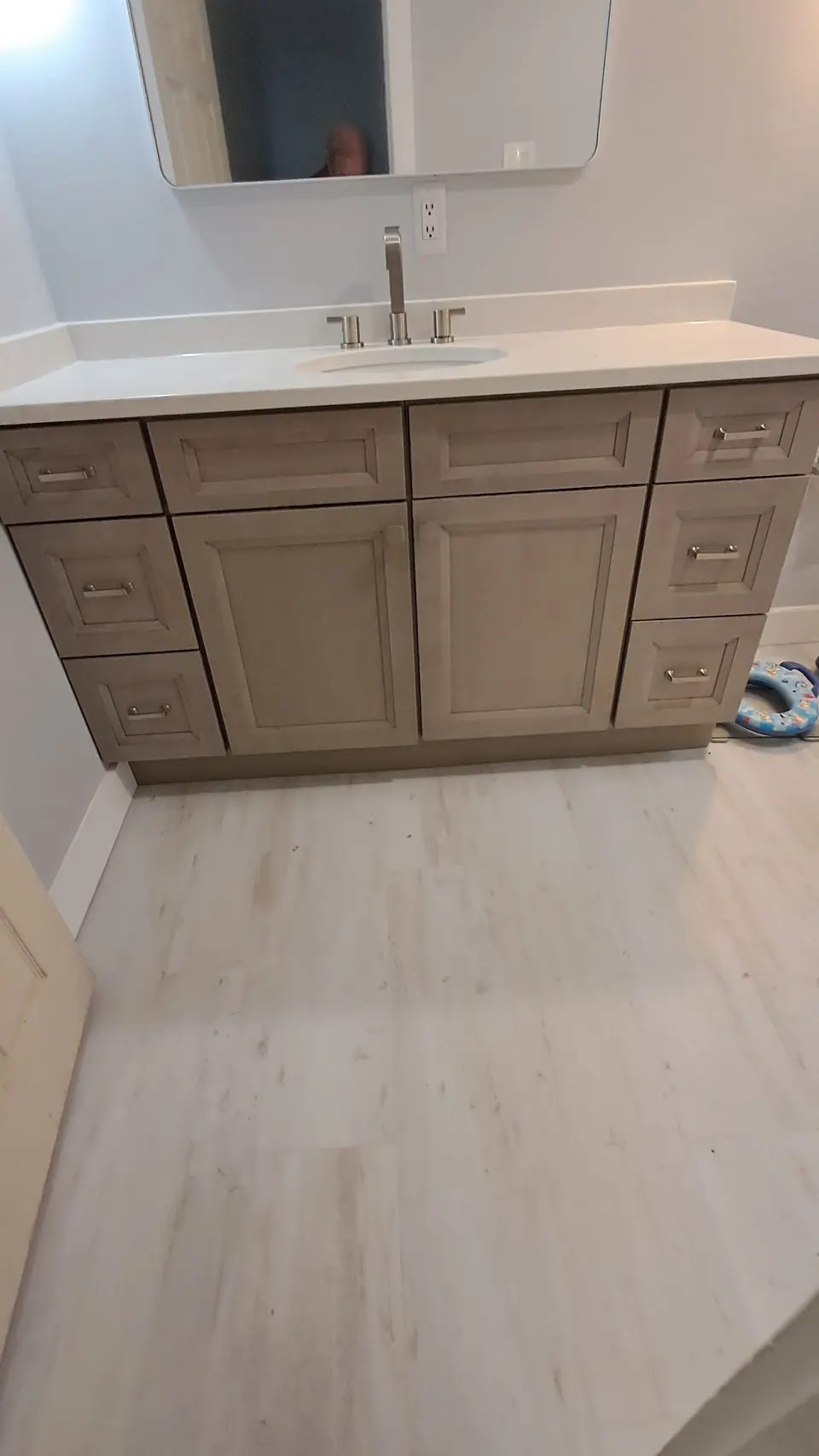 Greige shaker vanity with a white top under a wide mirror.