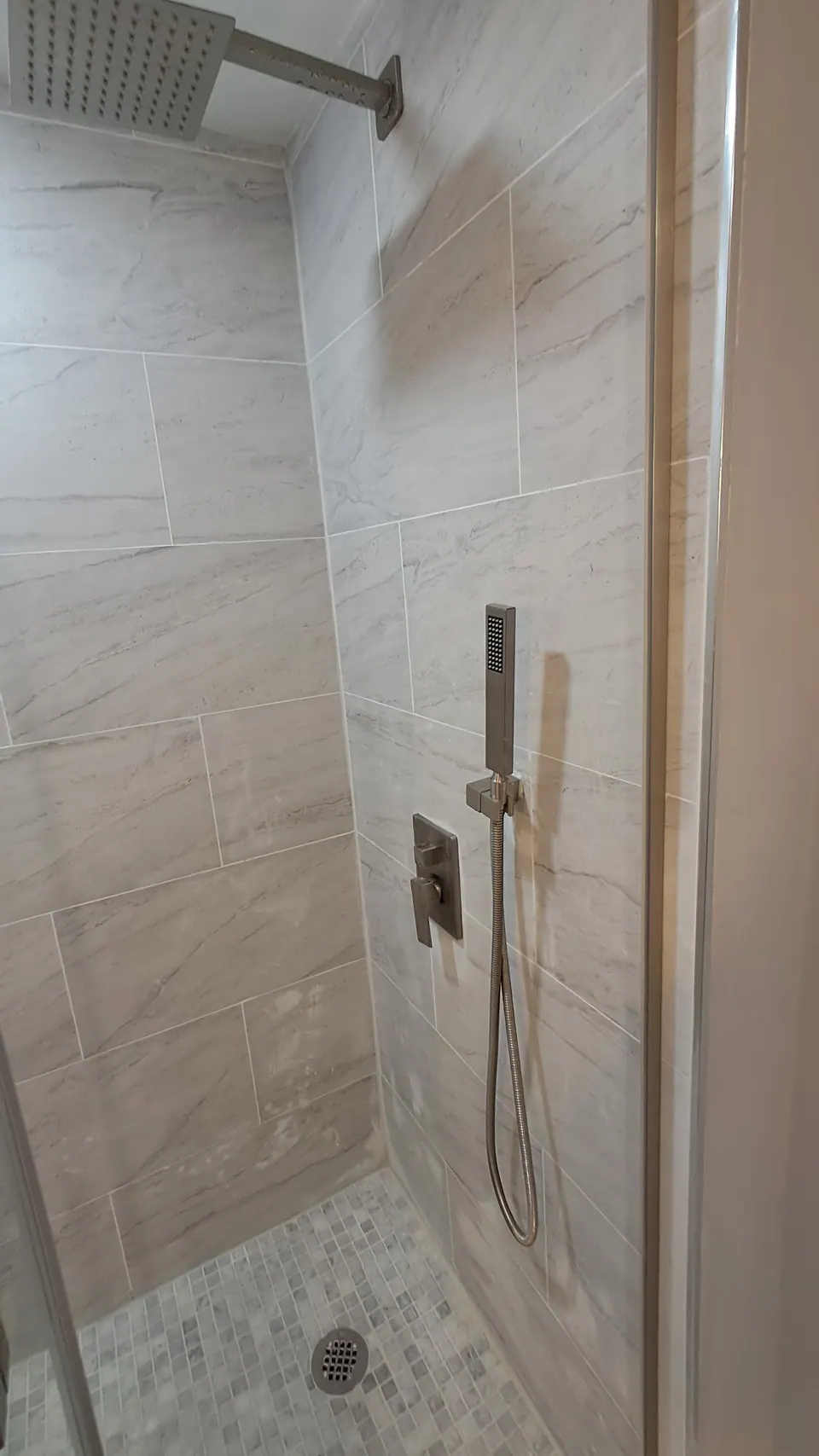 Tiled shower with a niche and a pebble floor.
