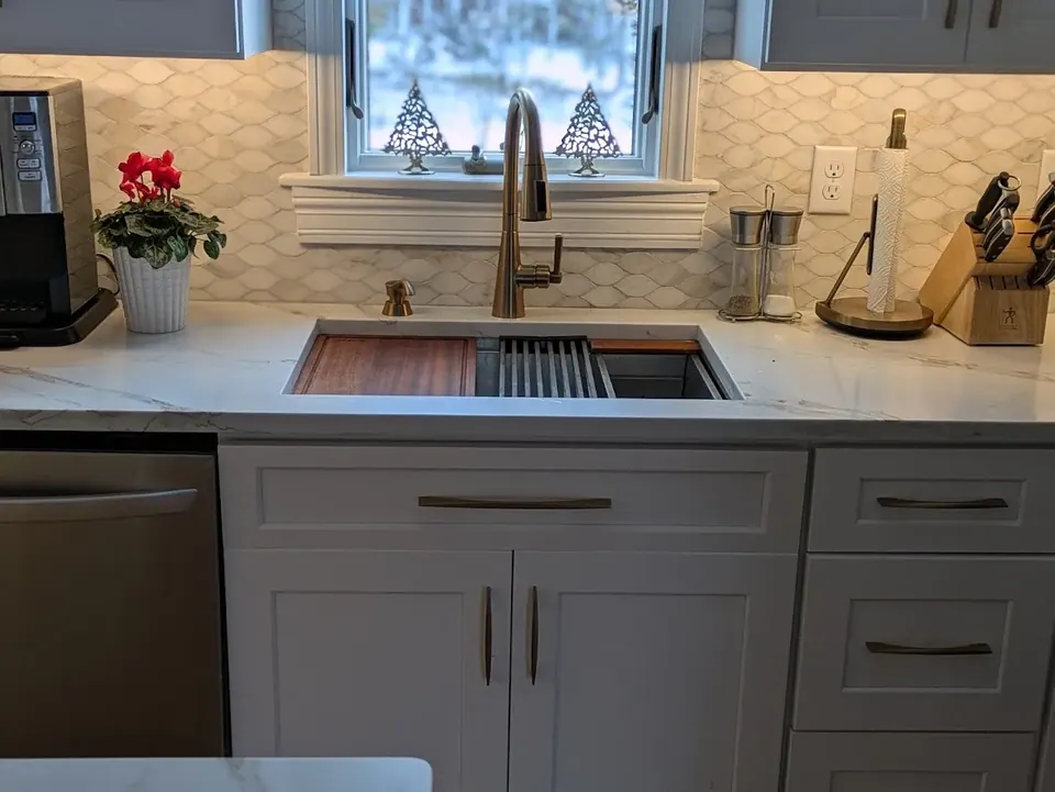 White shaker sink base and drawers under a window, with workstation sink and tile backsplash.
