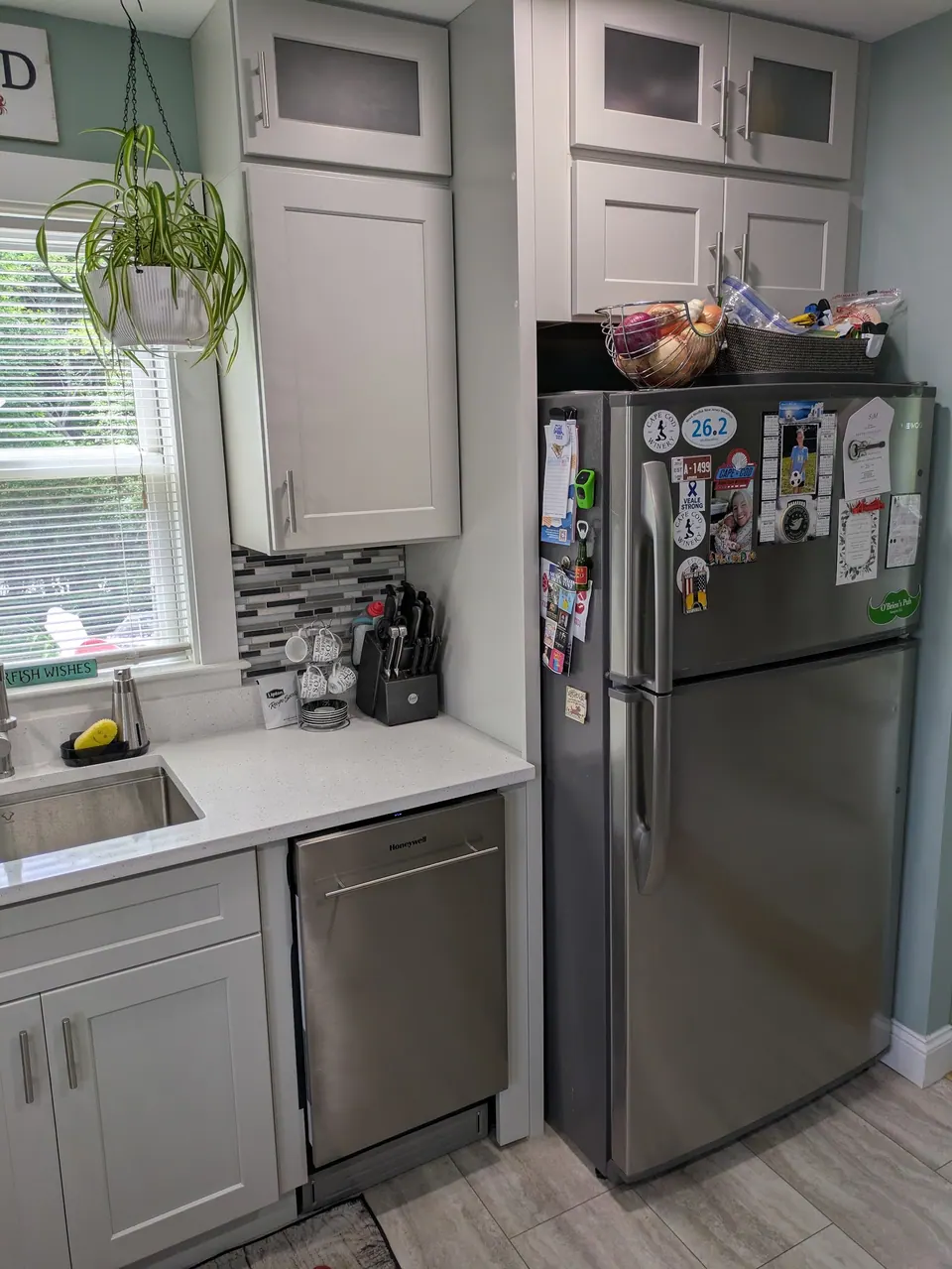 Tall white cabinets with a frosted glass top beside the refrigerator and dishwasher.