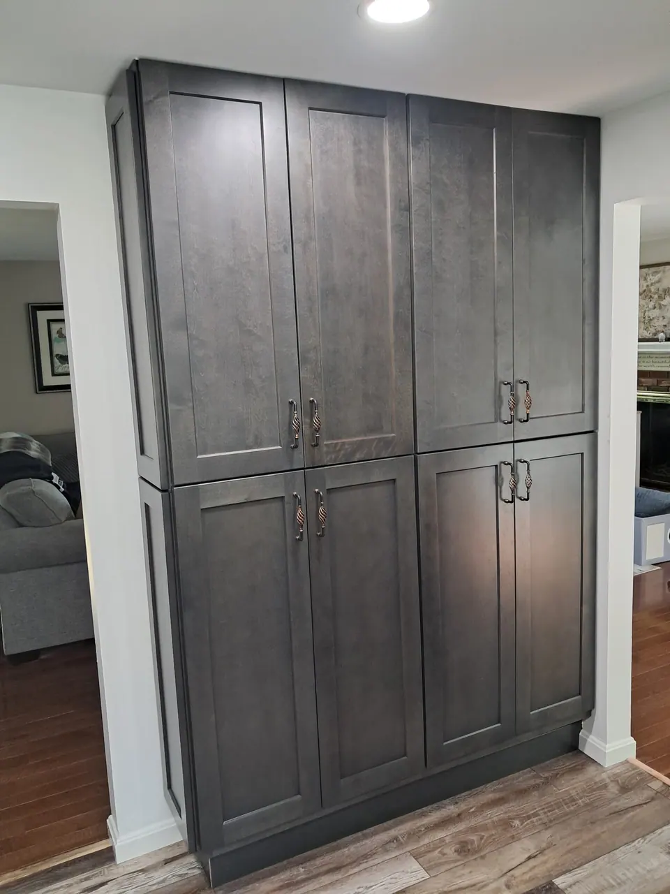 Tall wall of dark gray shaker pantry cabinets with eight doors and twisted metal pulls.