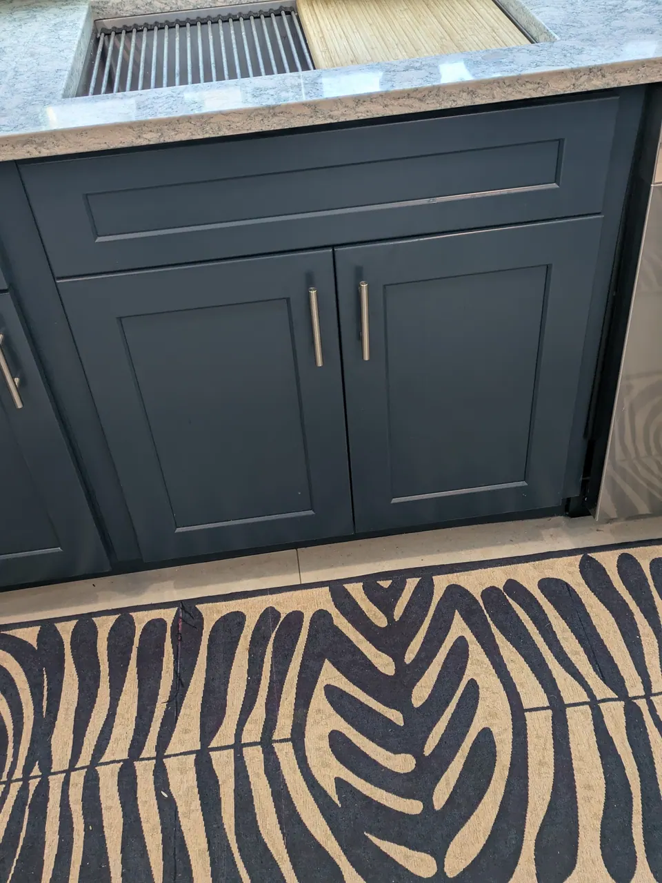 Navy blue sink base cabinet with two doors and bar pulls below a workstation sink.