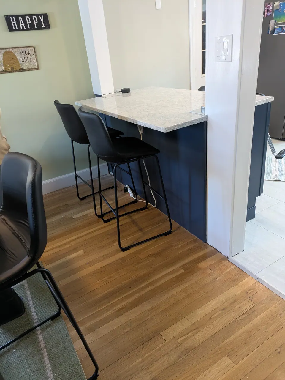 Peninsula seating side with two black counter stools under the countertop overhang, seen from the dining room.