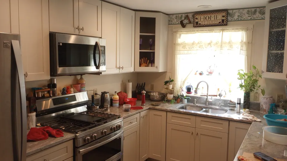Light gray shaker kitchen with a stainless range, over-the-range microwave and a window over the sink.