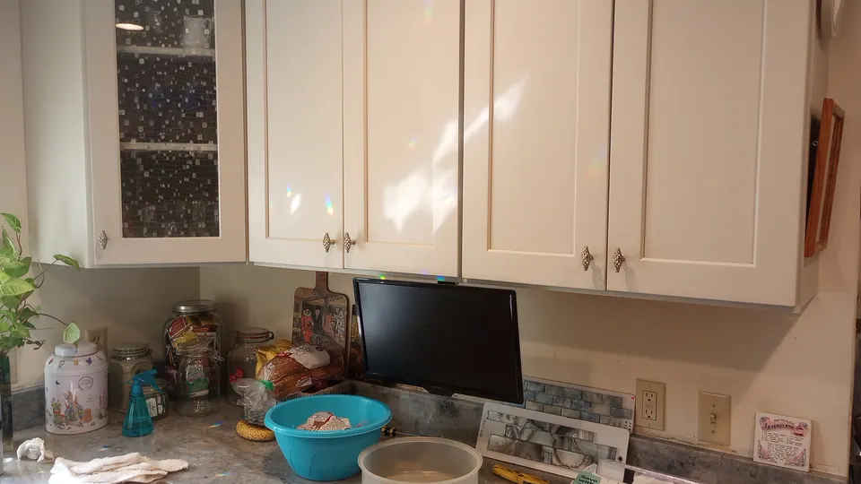 Light gray wall cabinets and a glass-front corner cabinet over the counter.