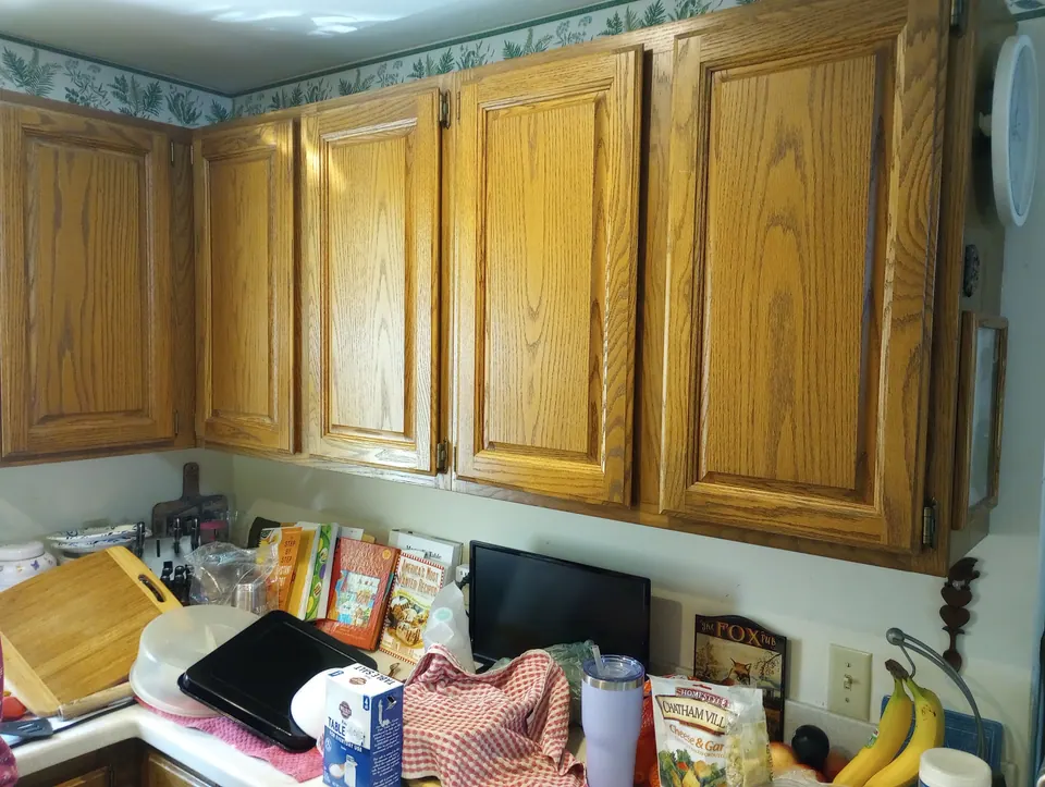 Before: oak wall cabinets over a cluttered counter.