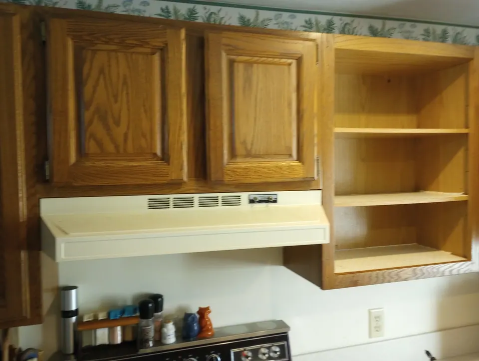 Before: oak cabinets and a white range hood.