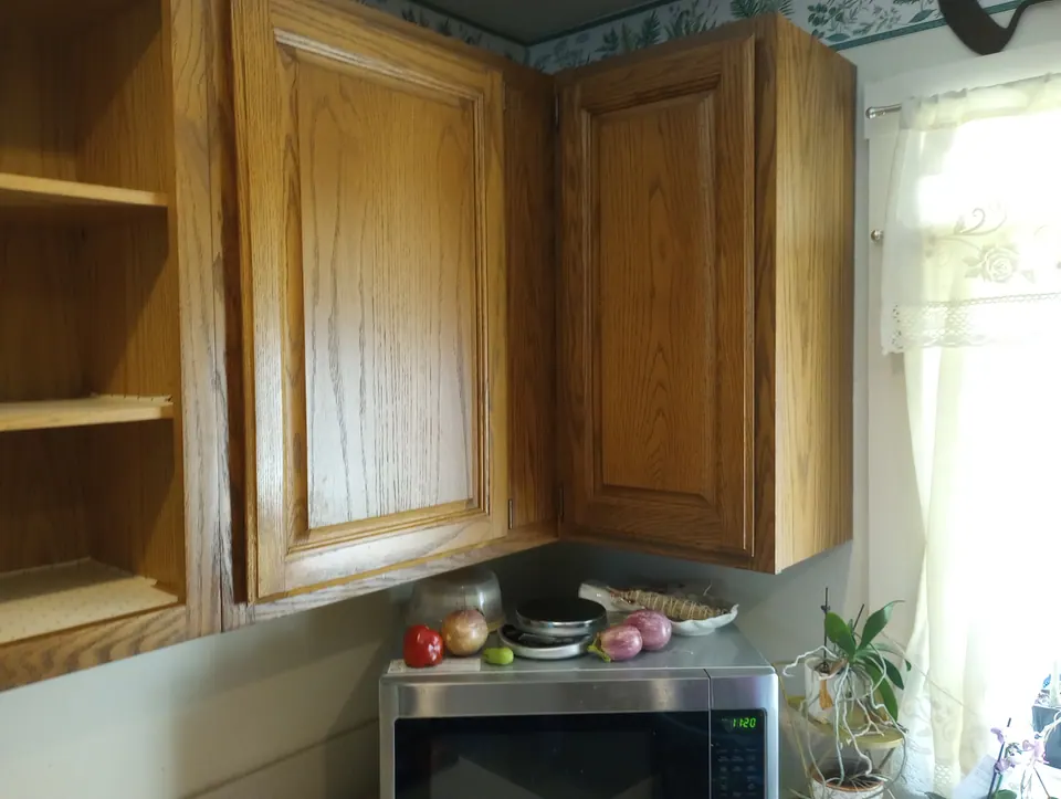 Before: oak corner cabinets by the window.