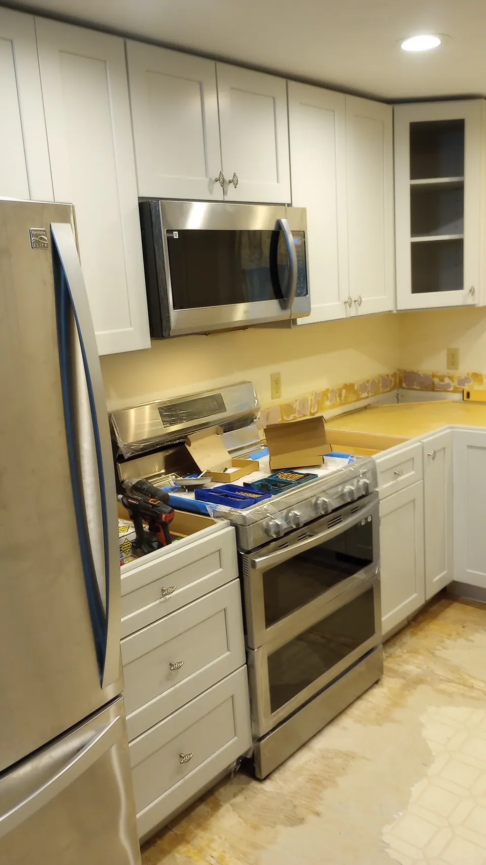 During the install: the range wall with new light gray cabinets.