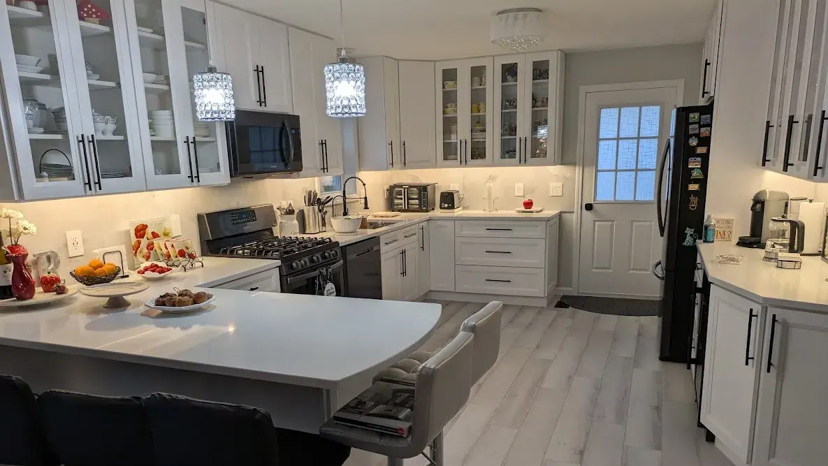 White shaker kitchen with glass-front cabinets, a peninsula and pendant lights, built in South Yarmouth.