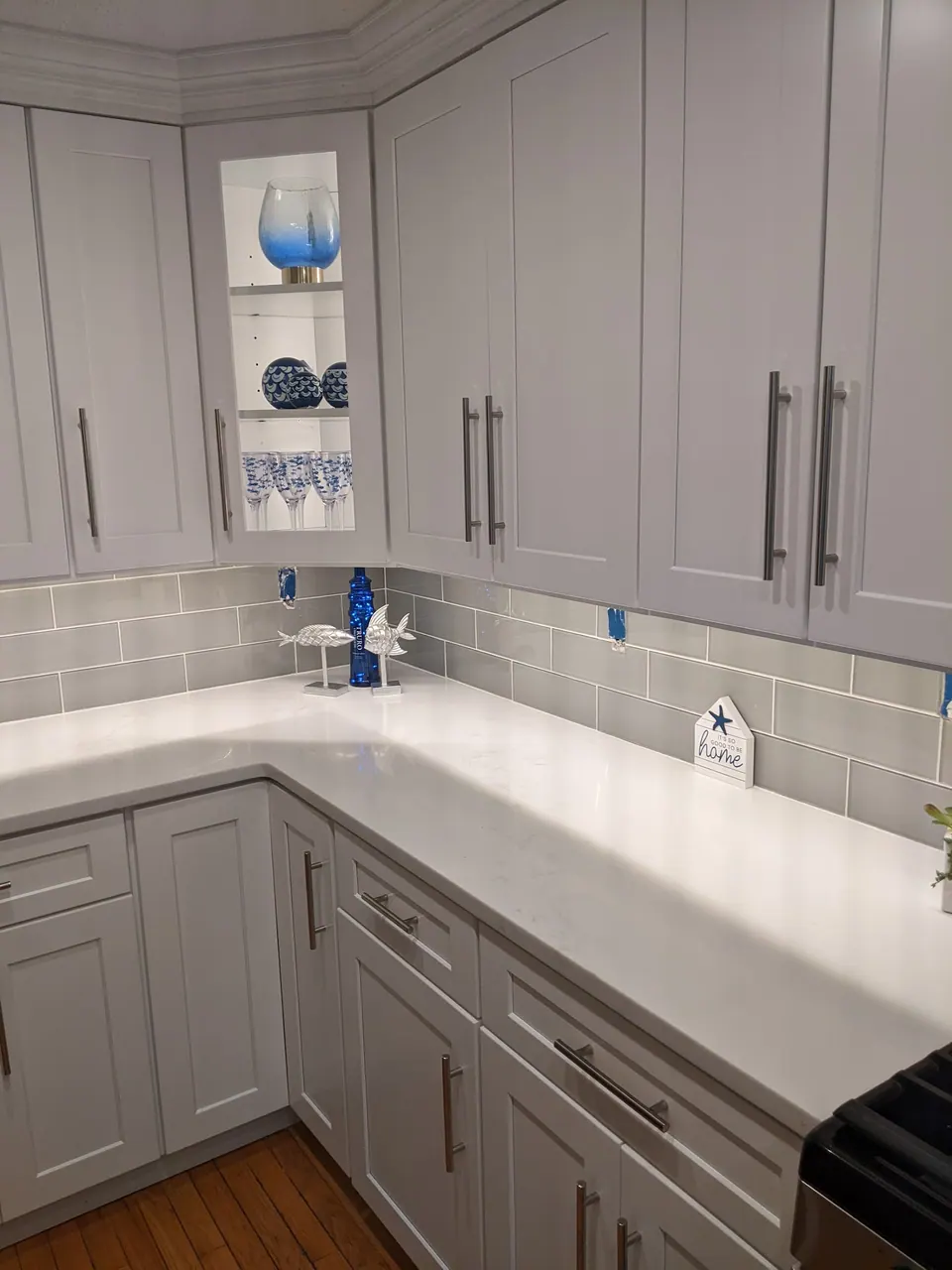 Lit glass-front corner cabinet over the L-shaped counter.