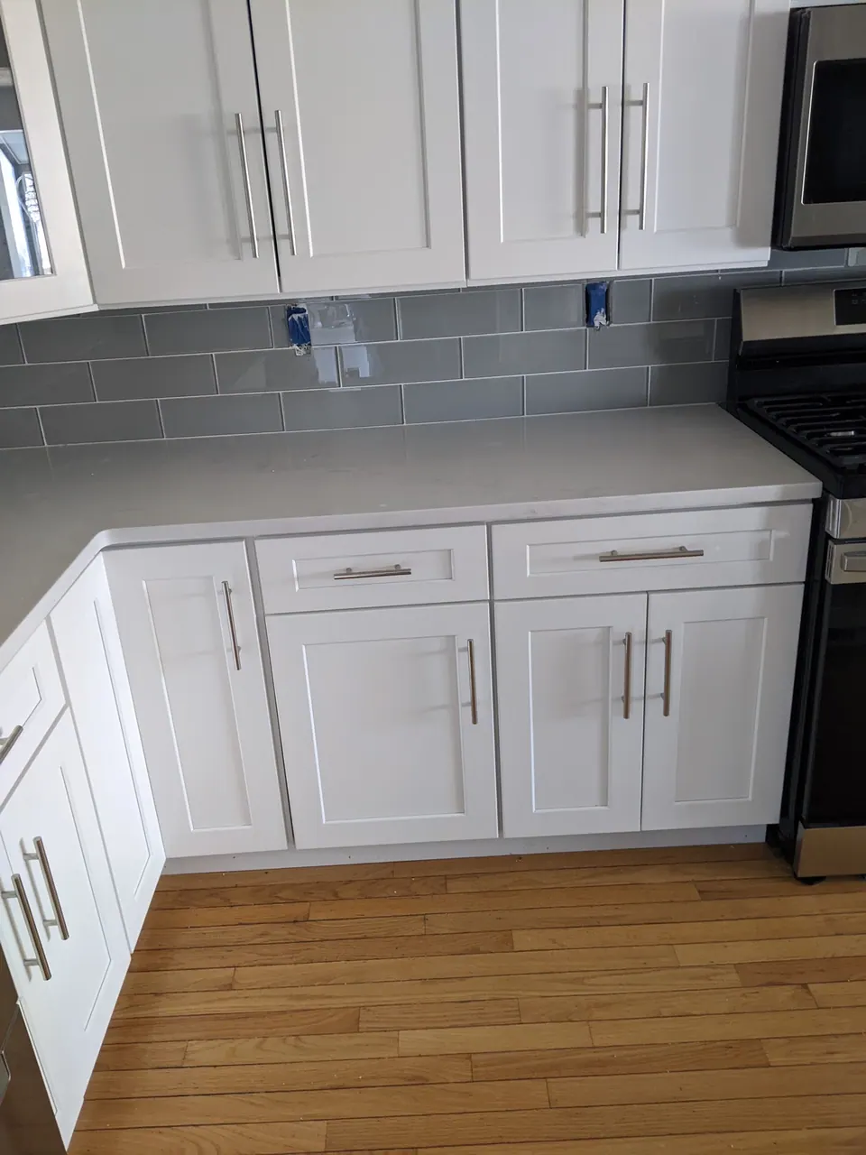 Corner of light gray cabinets with a quartz top.