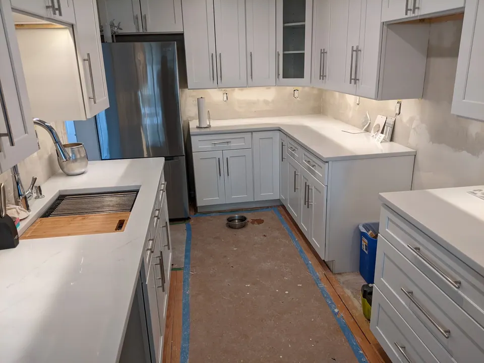 The new kitchen before the backsplash: light gray cabinets on an L.