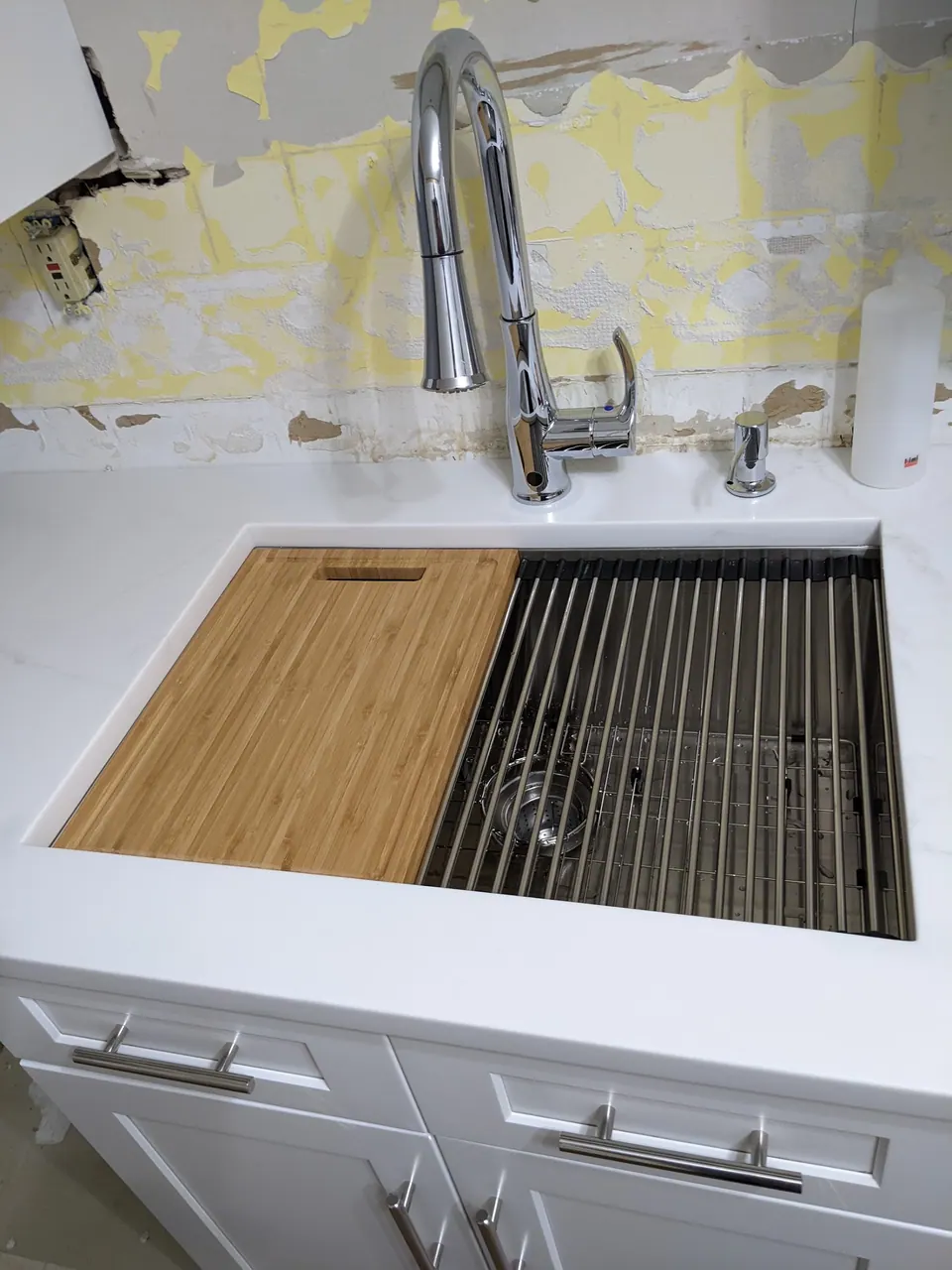 Workstation sink with a wood cutting board.