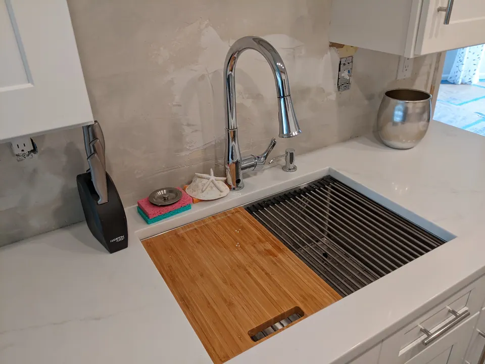 Faucet and workstation sink in the white quartz counter.
