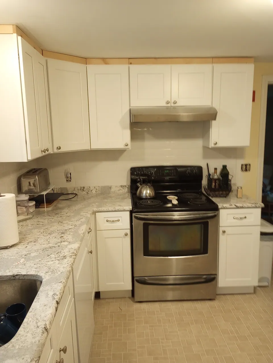 The kitchen from the doorway: white shaker cabinets on two walls.