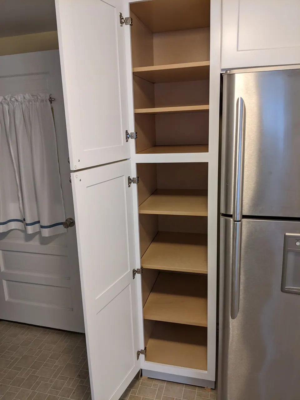 Tall white pantry open, with roll-out shelves.