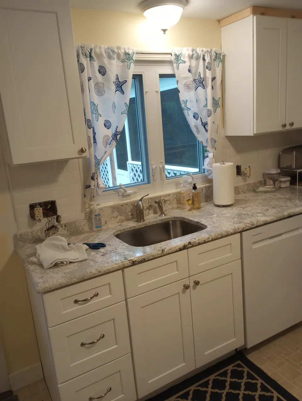 Sink under the window with white shaker cabinets.