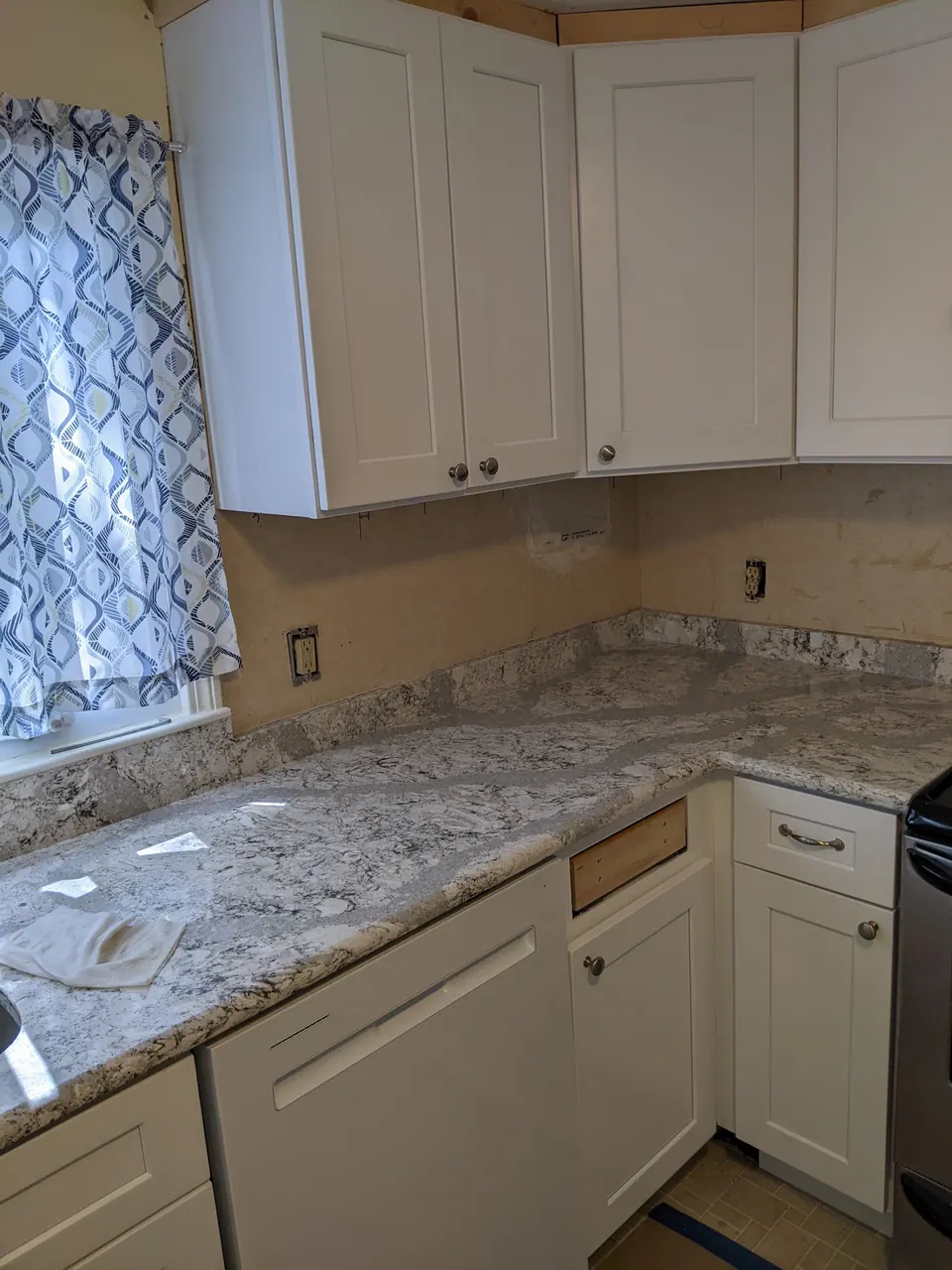Corner run of white shaker cabinets with a granite counter.