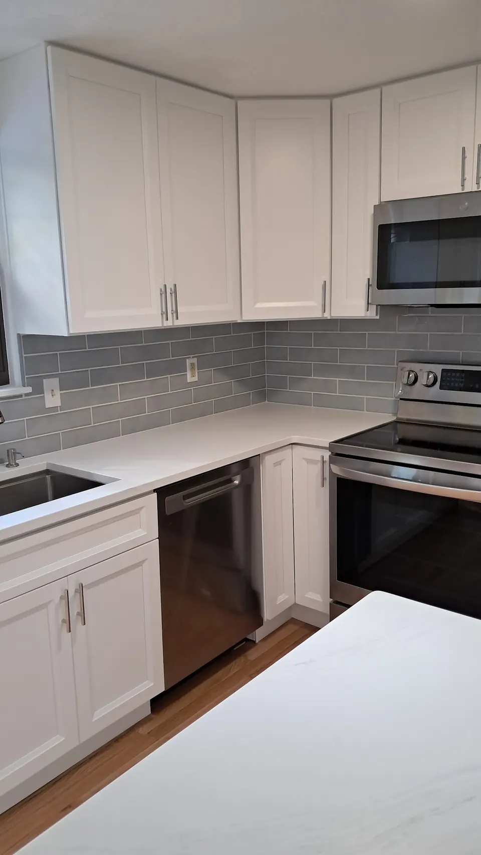 Corner of white shaker wall and base cabinets around the range and dishwasher.