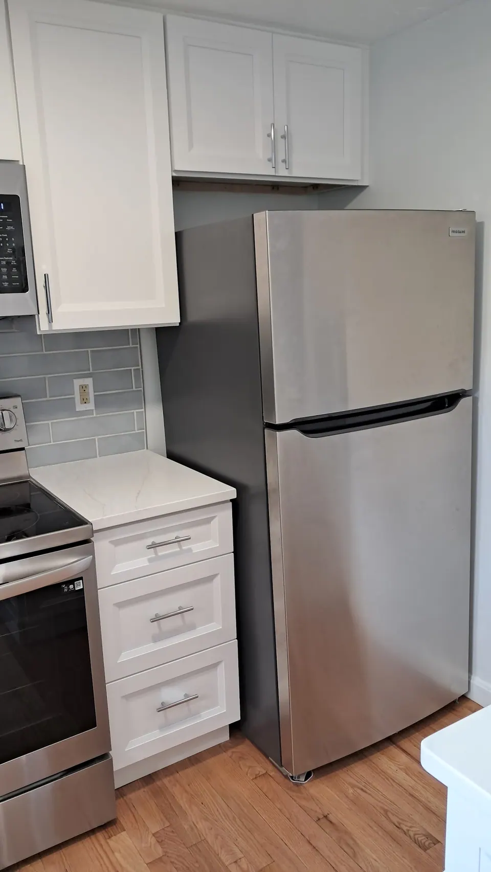 Tall white cabinets over the refrigerator next to a drawer base.