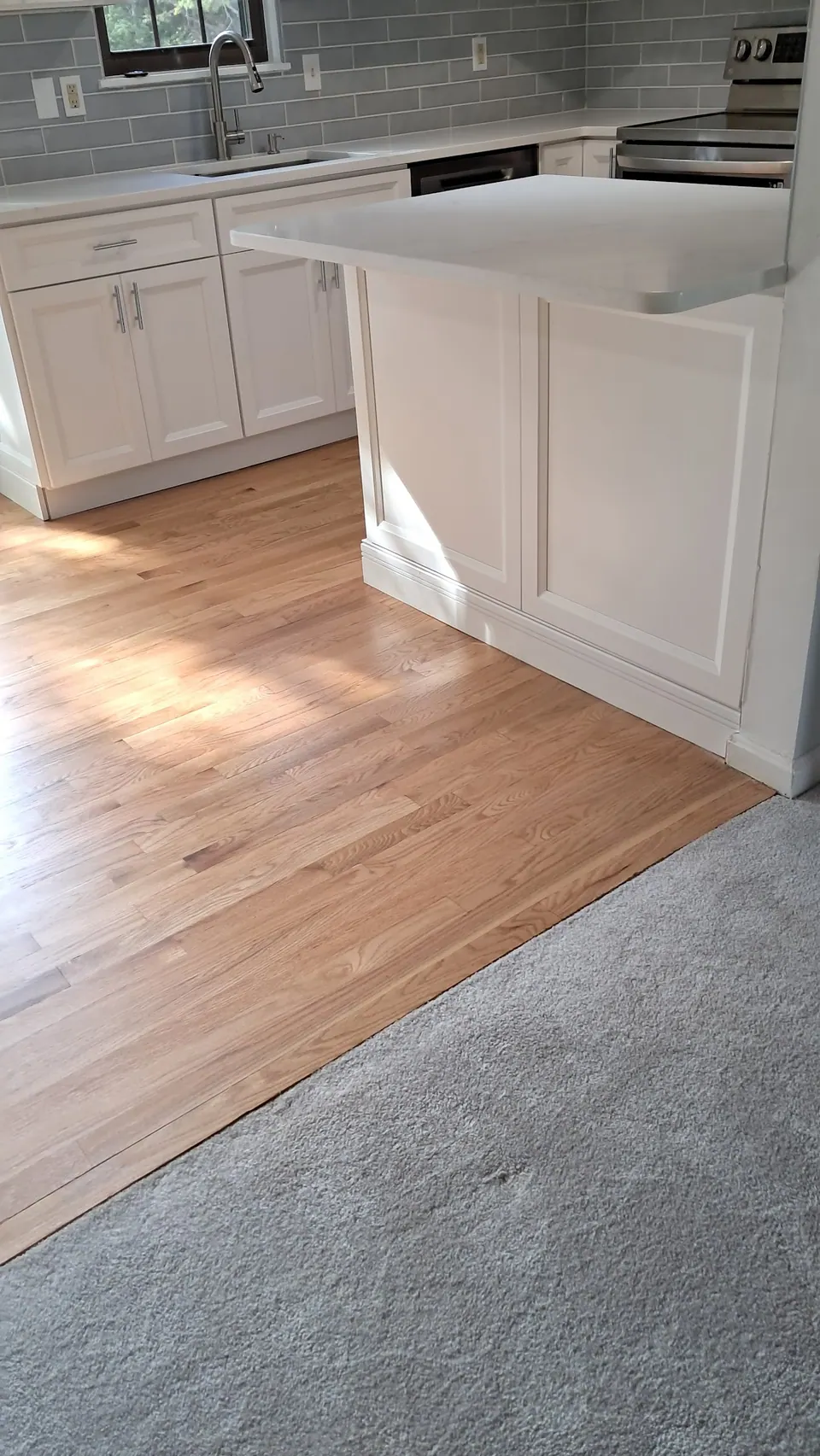 White island with raised panel sides and a quartz top on an oak floor.