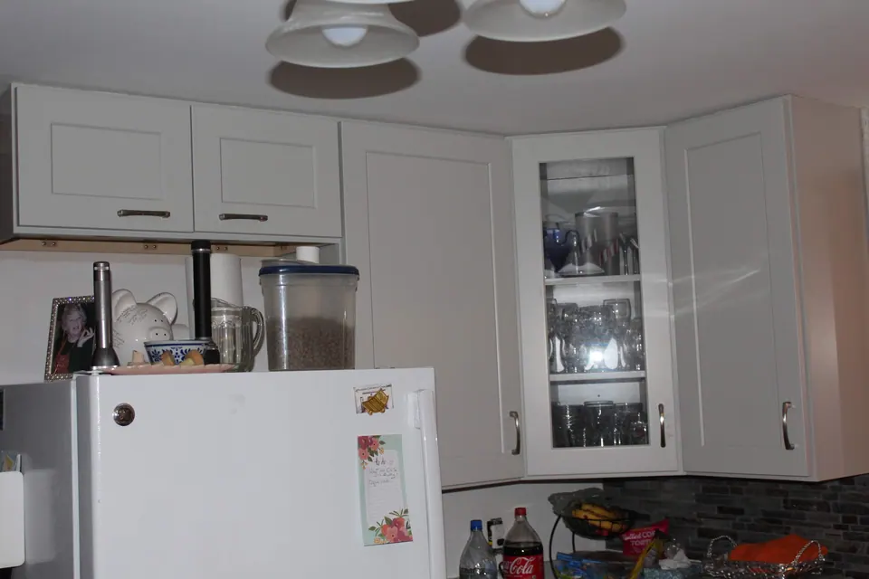 Light gray corner cabinets with a glass-front wall cabinet.