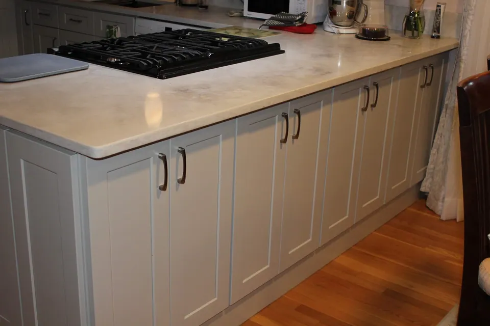 Long run of light gray base cabinets with a stone-look top and a cooktop.