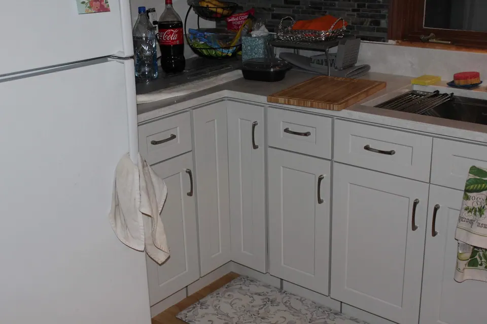 Corner of light gray base cabinets next to the refrigerator.