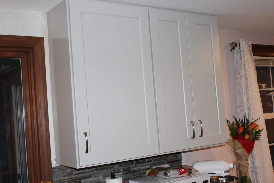Tall light gray shaker cabinets beside a wood doorway.