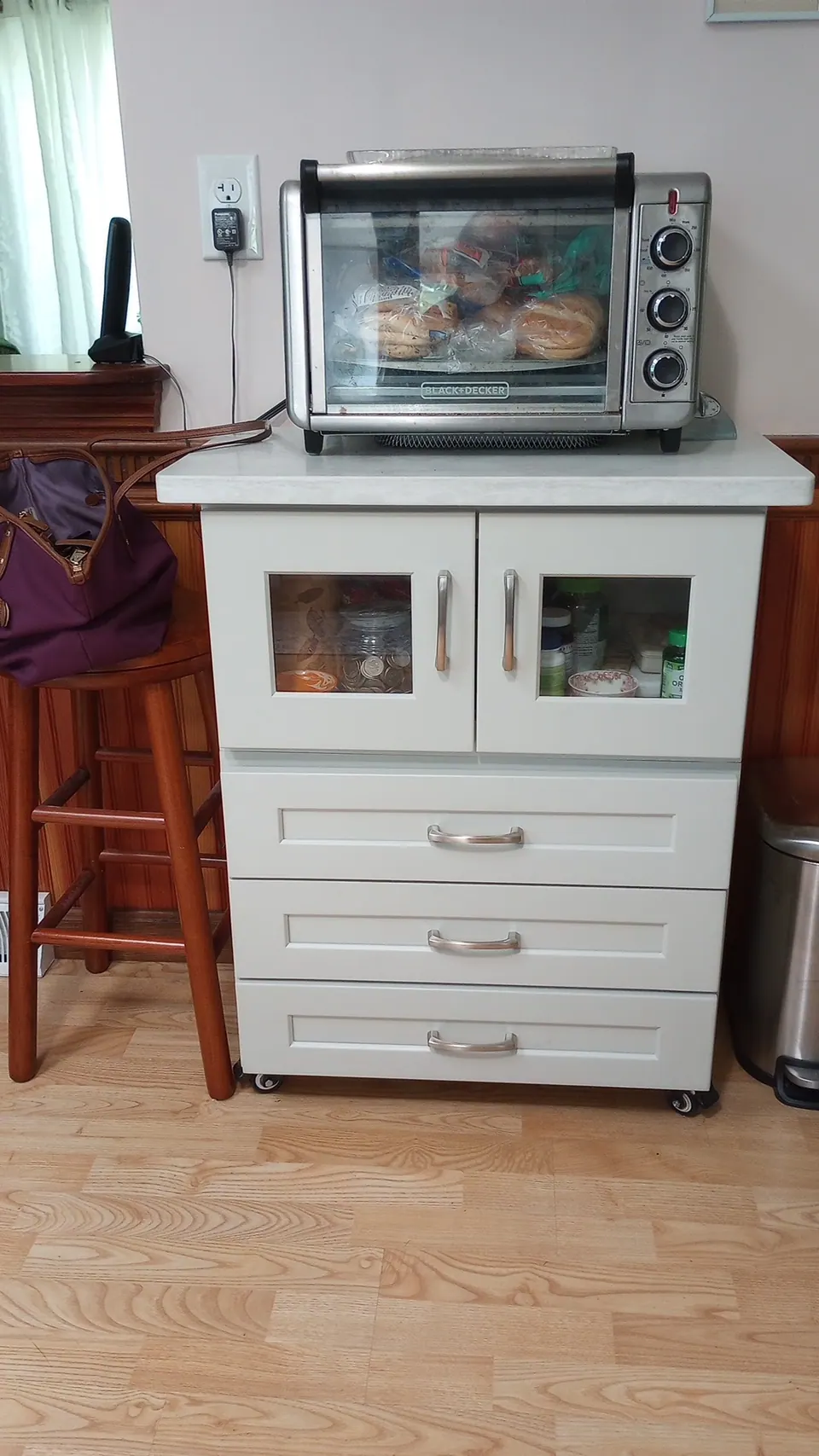 Freestanding light gray cabinet with glass doors and three drawers.