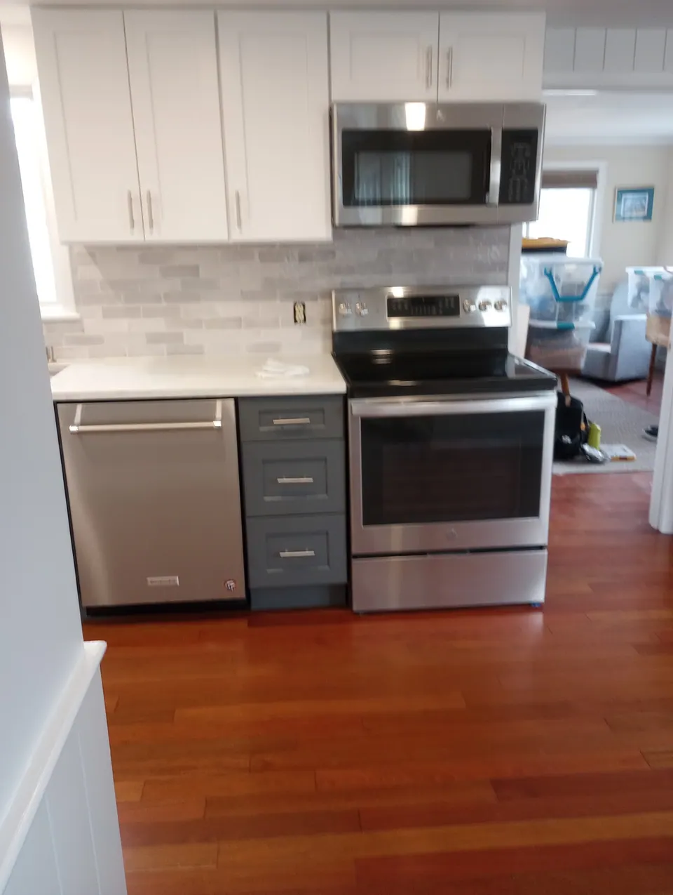 Range wall with white shaker wall cabinets, an over-the-range microwave and dark gray base cabinets.