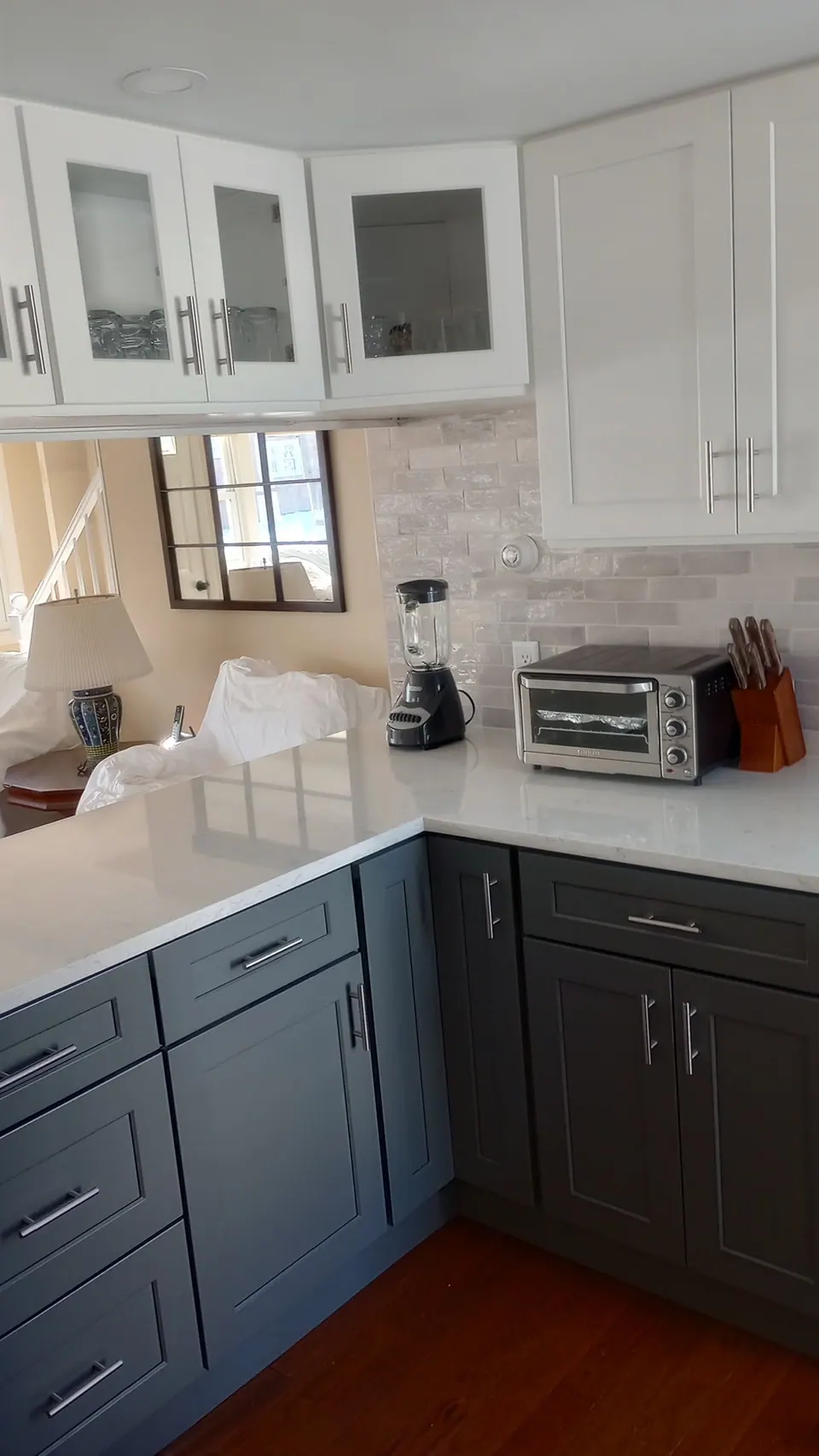 Glass-front white wall cabinets over the peninsula, dark gray base cabinets below.