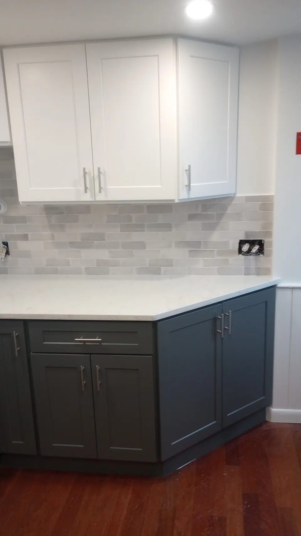 Corner run of dark gray base cabinets with white wall cabinets above.