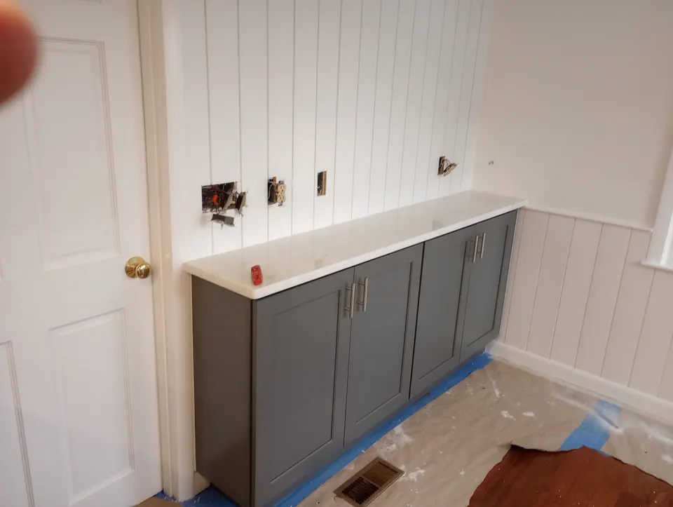 During the install: a run of dark gray base cabinets along a paneled wall.