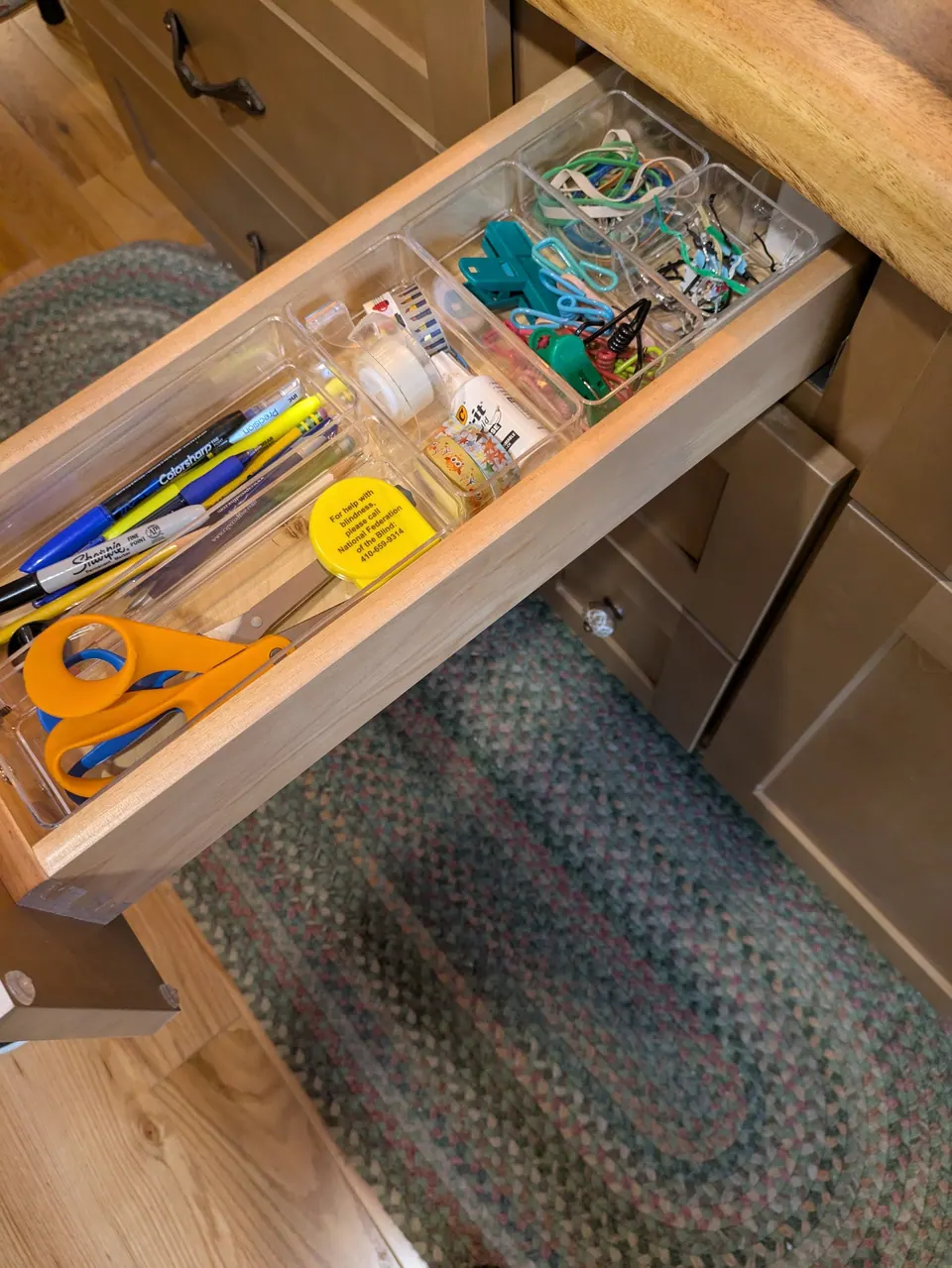 Open island drawer with a clear organizer holding pens, scissors and clips.