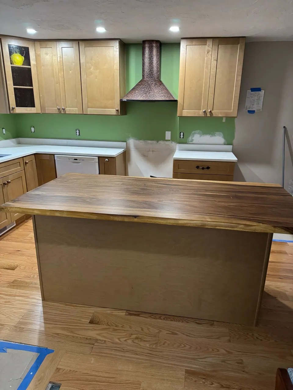 In progress: dark wood island top, light wood cabinets and hood installed, range opening still empty.