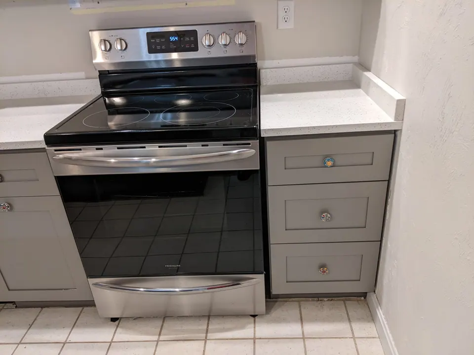 Range between gray shaker drawer bases with a white quartz top.