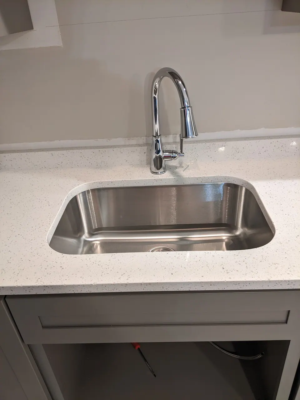 Stainless sink and faucet in the white quartz counter.