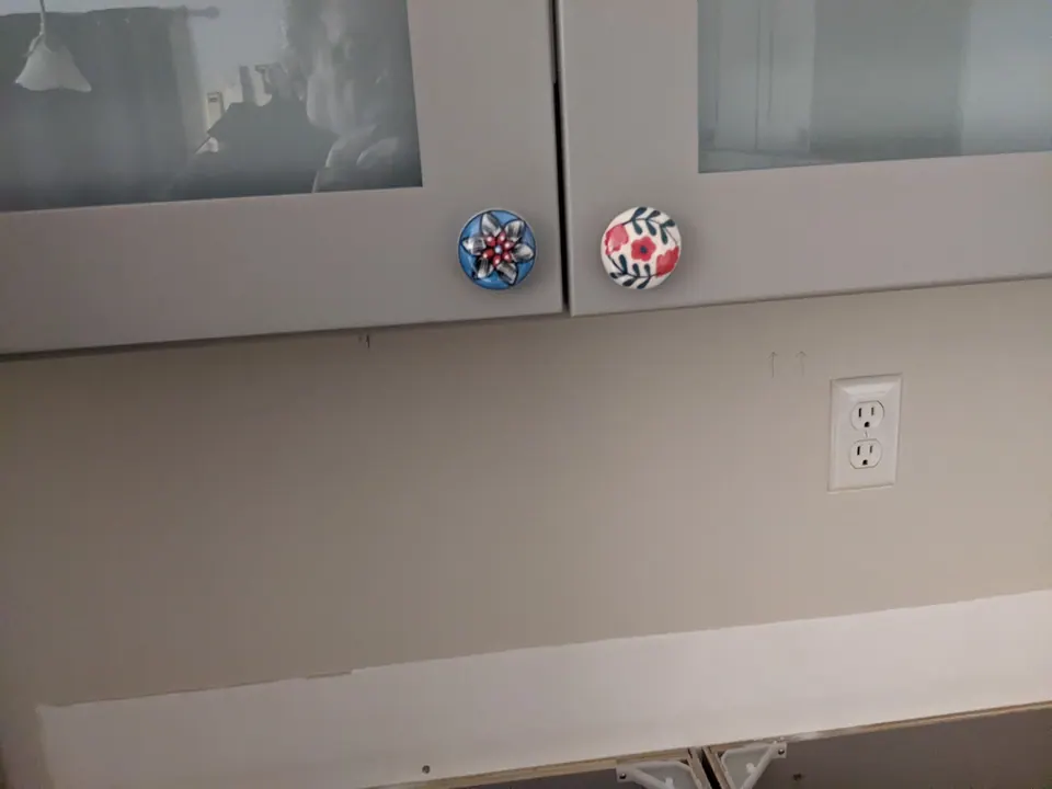 Gray wall cabinets with hand-painted knobs.