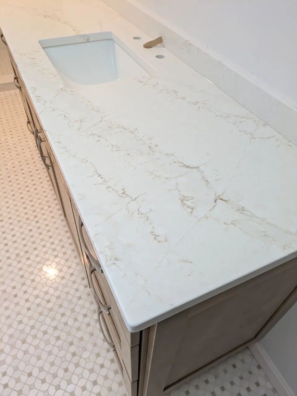 White marble-look top with an undermount sink on the natural wood vanity.