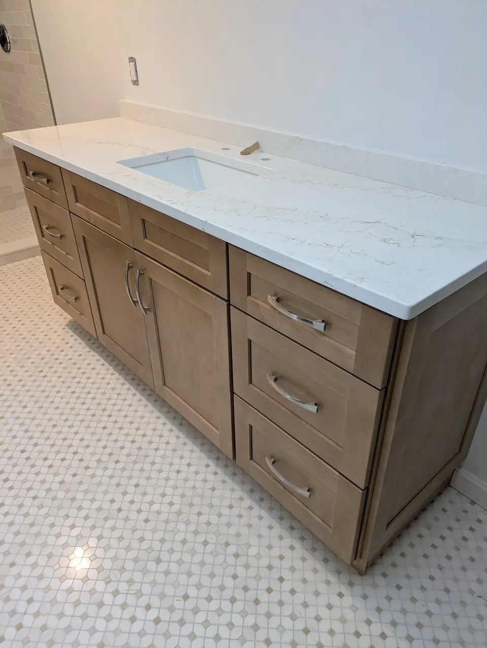 Drawer stack and doors of the natural wood vanity under the white top.