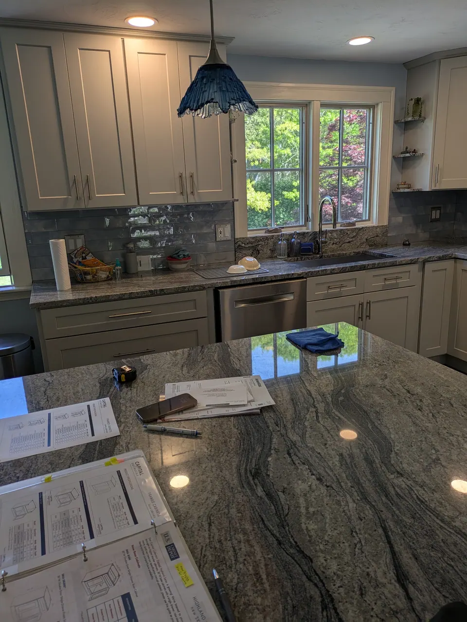Light gray cabinets around the sink window, seen across the gray veined peninsula countertop.