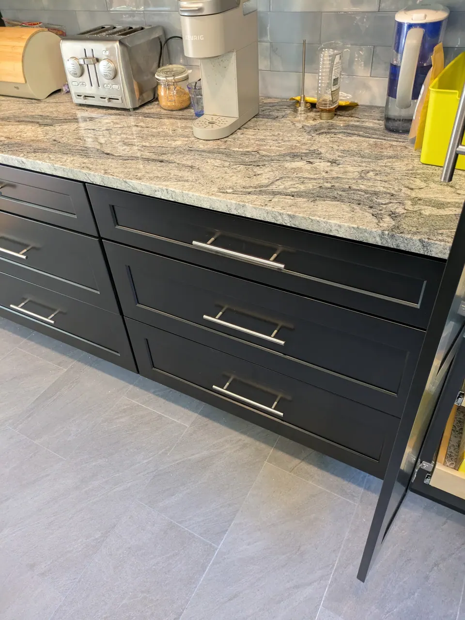 Two black drawer bases with bar pulls under the countertop, gray tile floor.