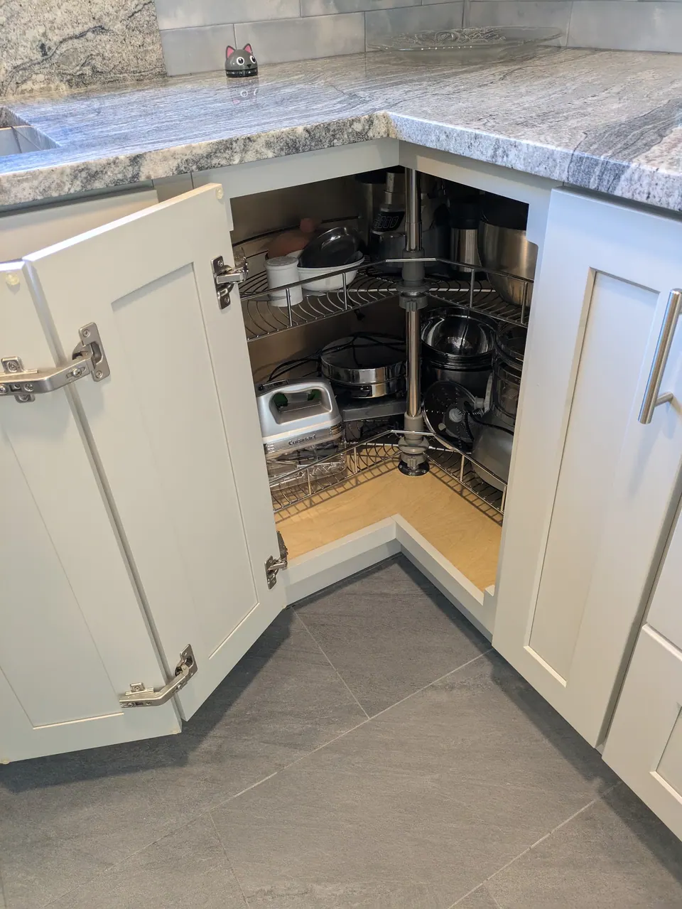 Light gray corner base cabinet open, showing a two-tier wire lazy Susan.