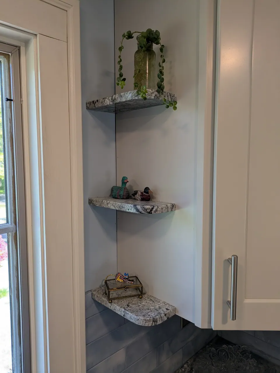 Three small corner shelves matching the countertop, beside a light gray wall cabinet.