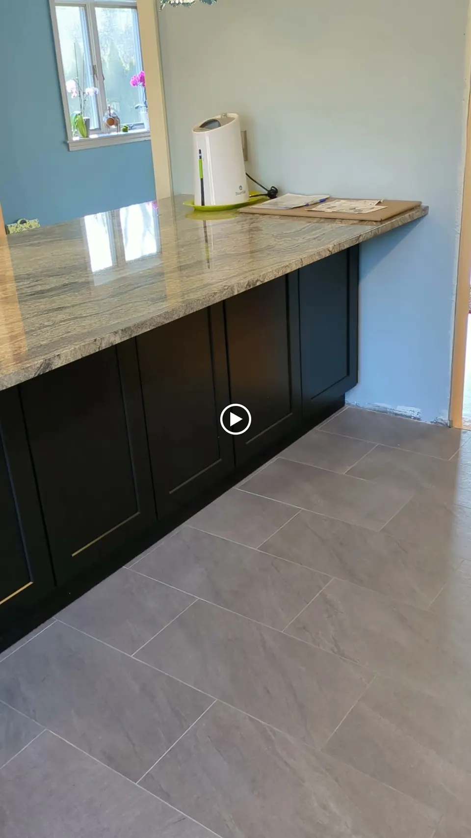 Back of the black peninsula: shaker doors under an overhanging gray veined countertop.