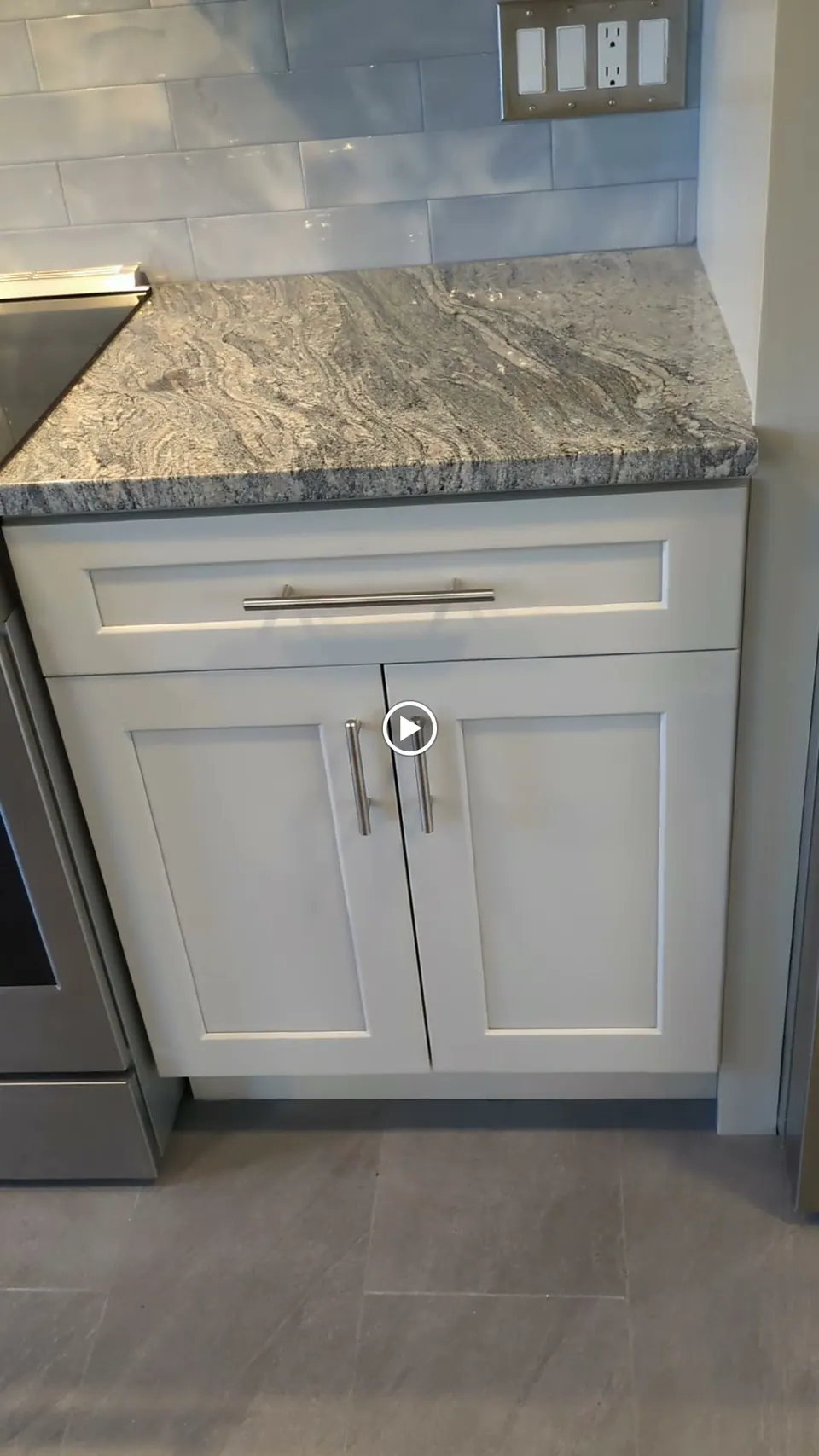 Light gray base cabinet with one drawer and two doors beside the range.