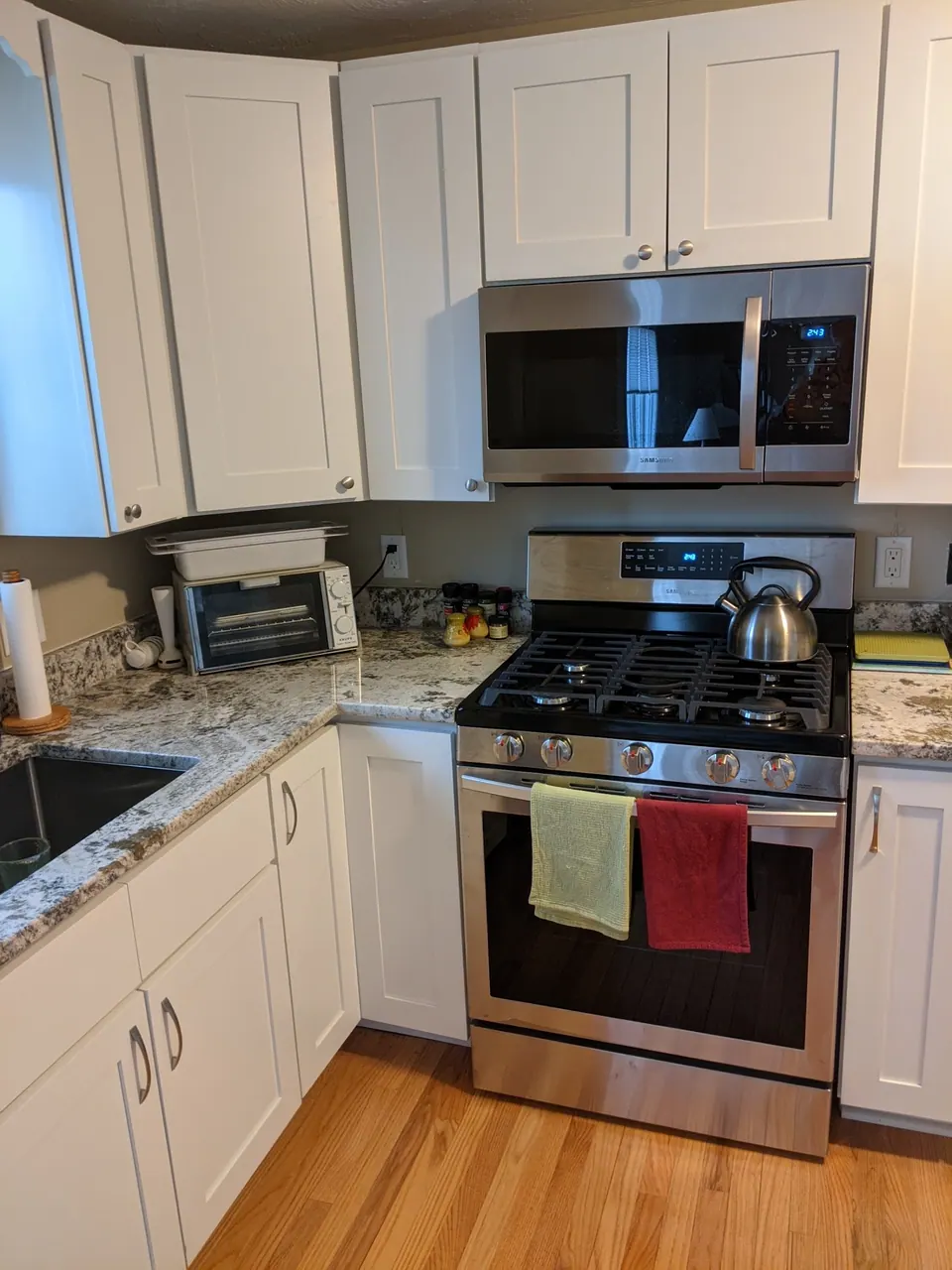 Range wall of white shaker cabinets with a stainless microwave and range.