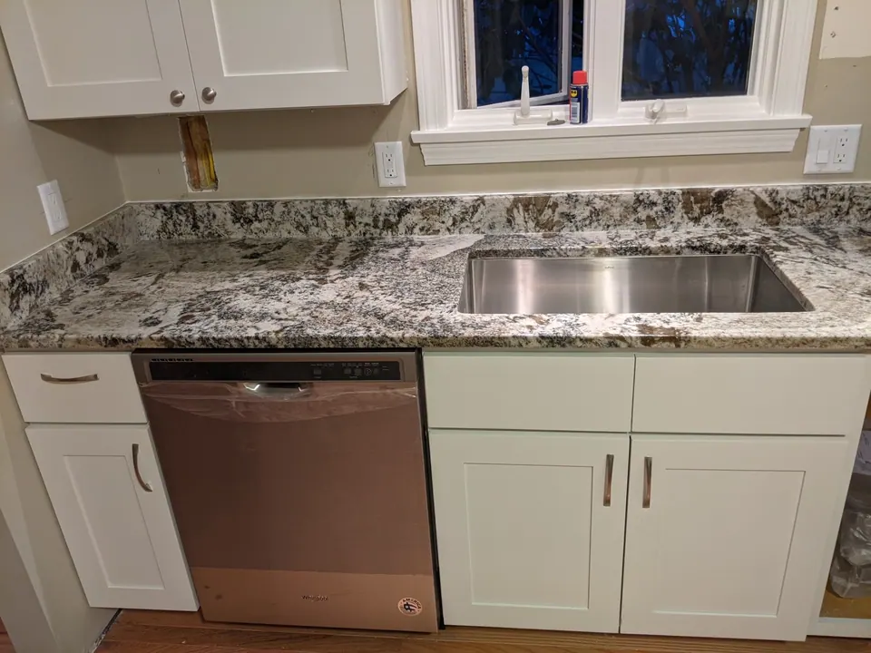 Sink and dishwasher in the white shaker base run.